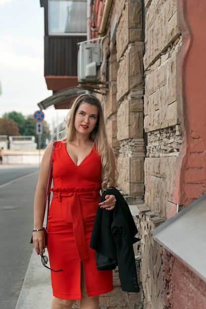 Młoda piękna dziewczyna o krętym kształcie ciała spacerująca po ulicy Czerwona seksowna dopasowana sukienka bez rękawów