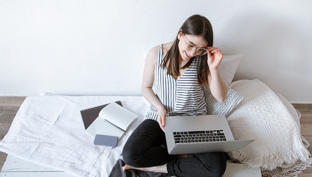 Młoda piękna dziewczyna pracuje zdalnie za laptopem w domu. Pojęcie freelancingu i pracy w Internecie.