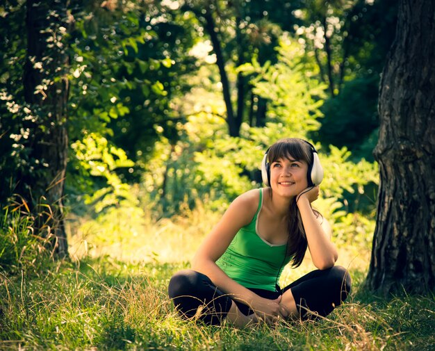 Młoda piękna dziewczyna słucha muzyki w parku