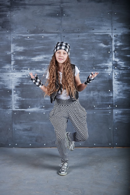 Młoda piękna dziewczyna tańczy w modne ubrania na ścianie grunge