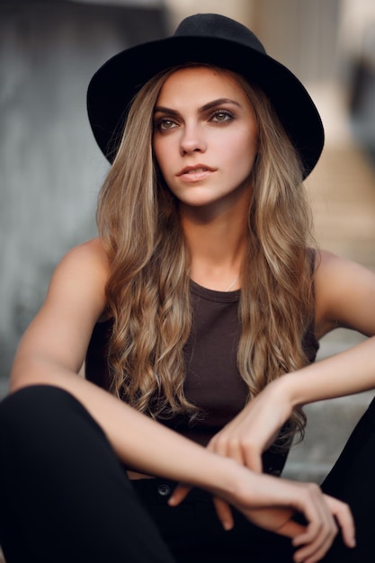 młoda piękna dziewczyna w krótkim eleganckim topie i czarnym kapeluszu