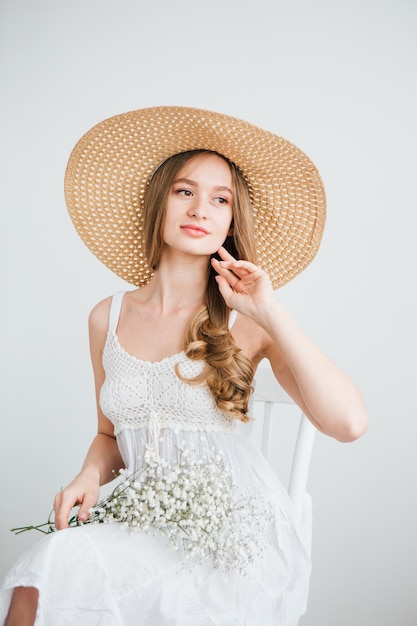 Młoda piękna dziewczyna z długimi włosami i kapelusz pozowanie z bukietem białych kwiatów. Tonowanie.