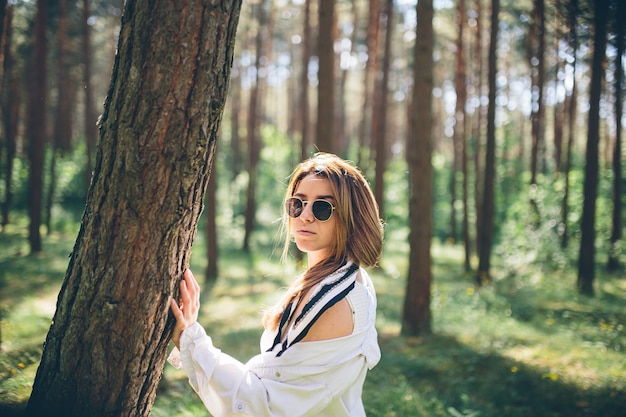 Młoda piękna hipis kobieta spaceruje po letnim lesie, śmieje się, tańczy i cieszy się życiem i naturą