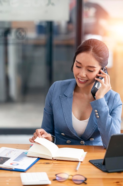 Młoda piękna i urocza bizneswoman uśmiecha się i rozmawia przez telefon komórkowy w biurze