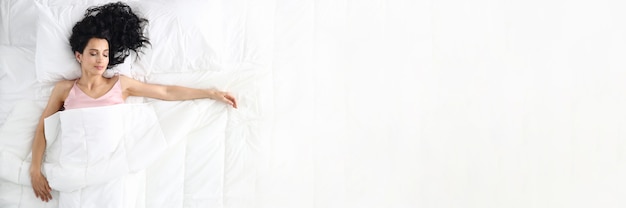 Zdjęcie młoda piękna kaukaski kobieta śpi na białym łóżku portret domu. widok z góry