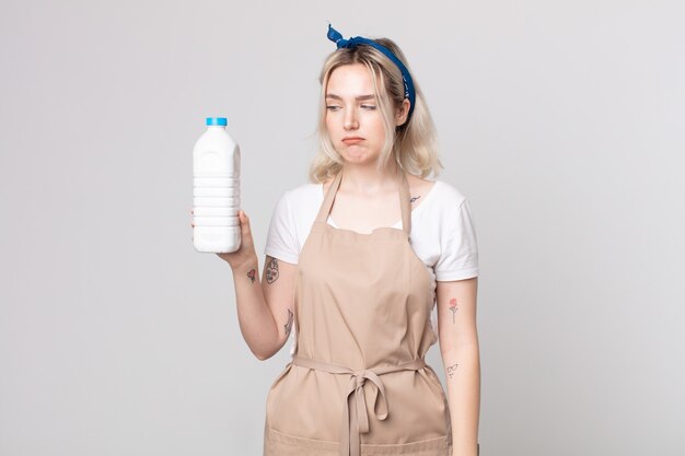 Młoda piękna kobieta albinos czuje się smutna, zdenerwowana lub zła i patrzy w bok z butelką mleka