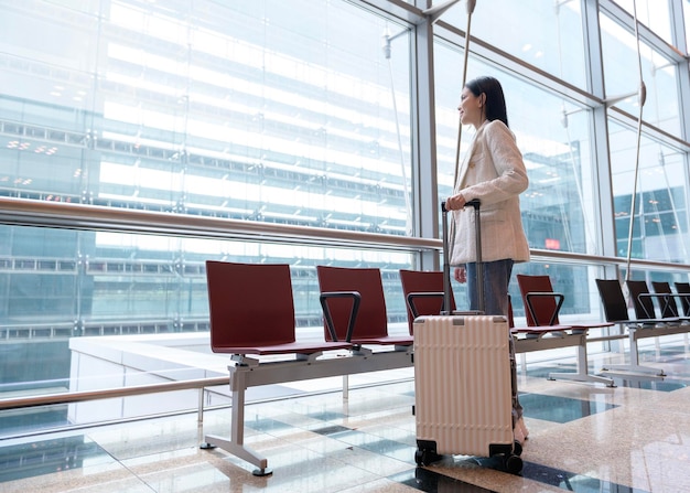 Młoda piękna kobieta chodząca z walizką odprawia się na międzynarodowym lotnisku