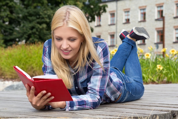 Młoda piękna kobieta czyta książkę w parku
