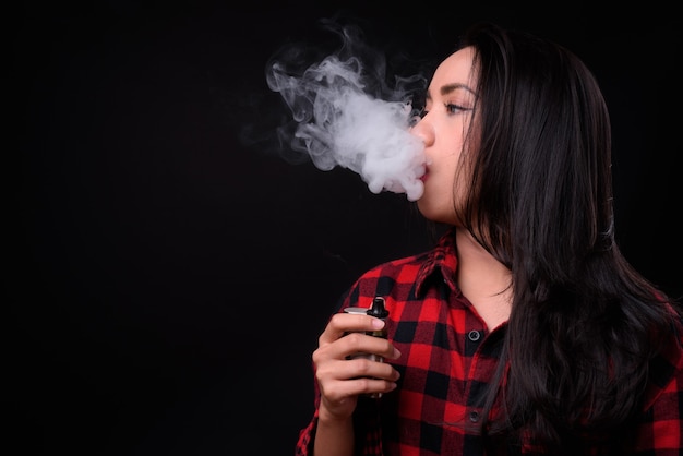 młoda piękna kobieta Filipino vaping na czarnej ścianie