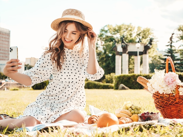 Młoda piękna kobieta hipster w modne letnie dżinsy, różowy T-shirt i kapelusz. Beztroska kobieta robi piknik na zewnątrz.