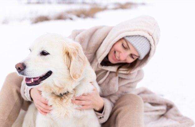 Zdjęcie młoda piękna kobieta i jej pies golden retriever bawią się zimą