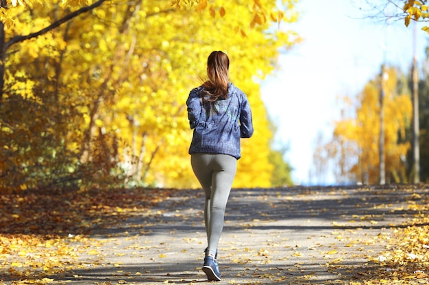 Młoda piękna kobieta jogging w jesiennym parku