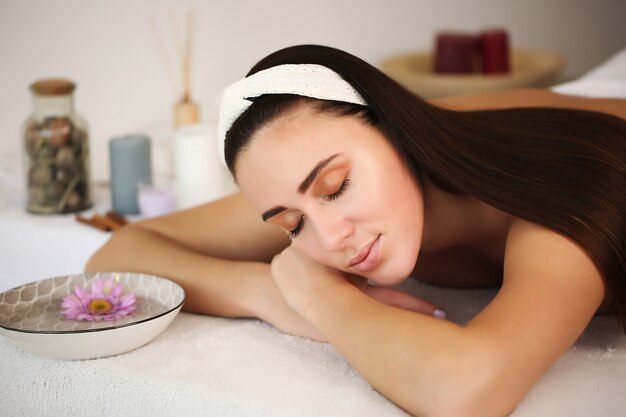 Młoda piękna kobieta korzystających z masażu na stole w centrum spa