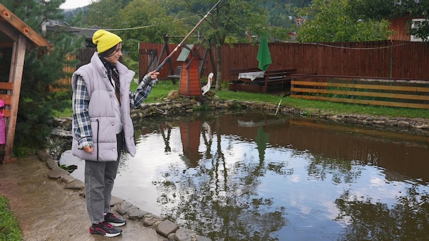 Młoda piękna kobieta łowi ryby w małym stawie