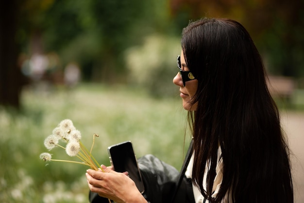 Młoda piękna kobieta na trawniku z dandelions Blowing Dokonanie życzenia