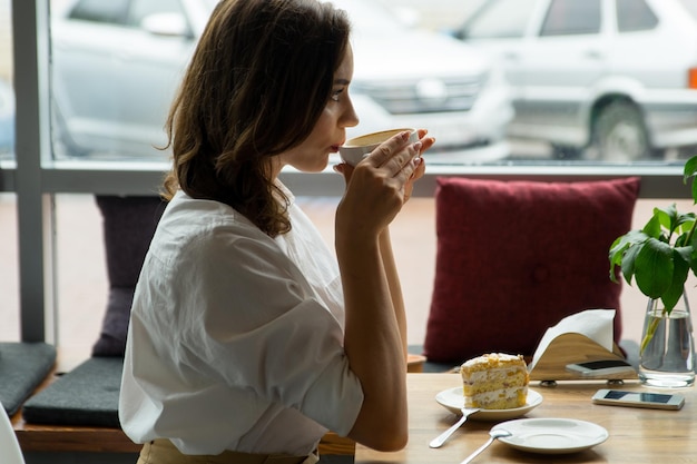 Młoda piękna kobieta pije kawę w kawiarni młoda kobieta w biznesowych ubraniach podczas przerwy na lunch