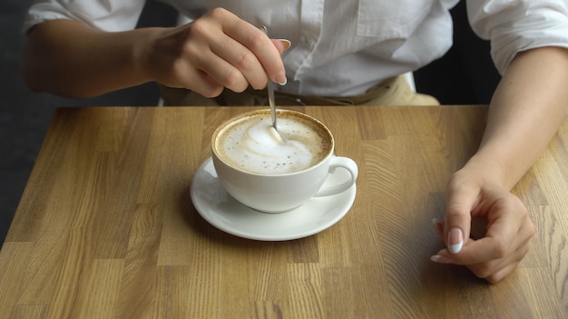 Młoda piękna kobieta pije kawę w kawiarni Ręka dziewczyny mieszającej cukier w kawie z bliska
