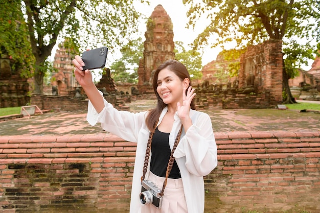 Zdjęcie młoda piękna kobieta podróżująca i robiąca zdjęcie w tajskim historycznym parku