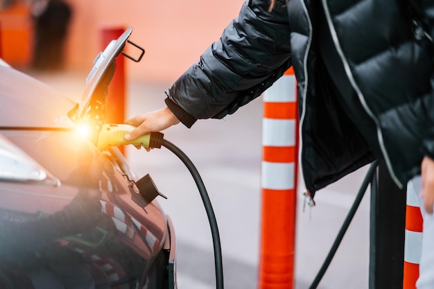 Młoda piękna kobieta podróżująca samochodem elektrycznym po zatrzymaniu się na stacji ładującej