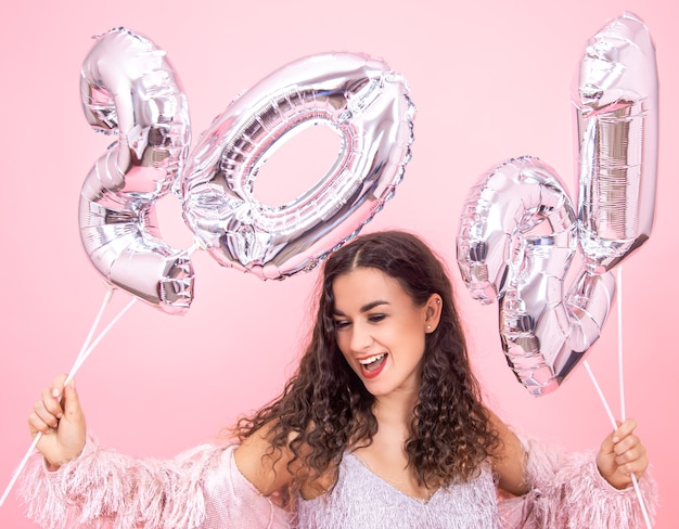 Młoda Piękna Kobieta Raduje Się W Nowym Roku Na Różowej ścianie Ze Srebrnymi Balonami Dla Koncepcji Nowego Roku
