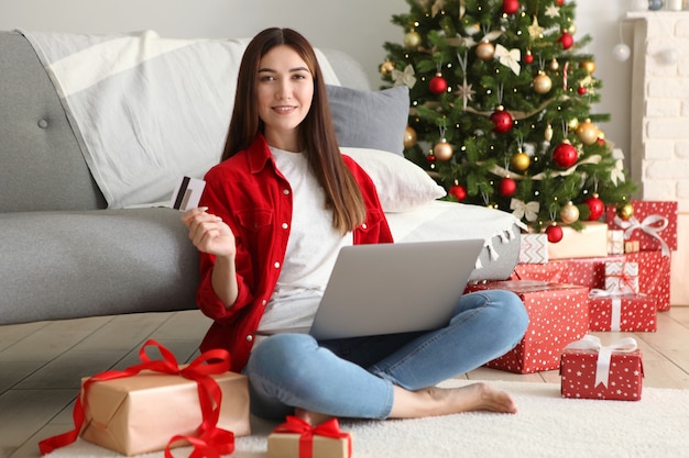 Młoda piękna kobieta robi zakupy na Boże Narodzenie w świątecznym wnętrzu w domu