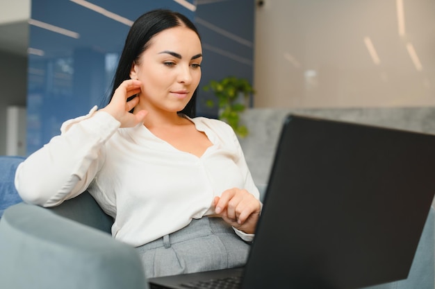 Młoda piękna kobieta siedzi w centrum handlowym i pracuje na laptopie przy użyciu telefonu komórkowego Freelance i koncepcja biznesowa