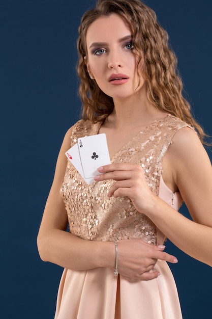 Młoda piękna kobieta trzyma zwycięską kombinację kart pokera na ciemnoniebieskim tle. Dwa asy