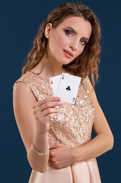 Młoda piękna kobieta trzyma zwycięską kombinację kart pokera na ciemnoniebieskim tle. Dwa asy