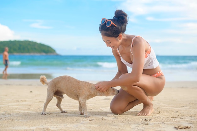 Młoda piękna kobieta w bikini z psem, ciesząc się i relaksując na plaży