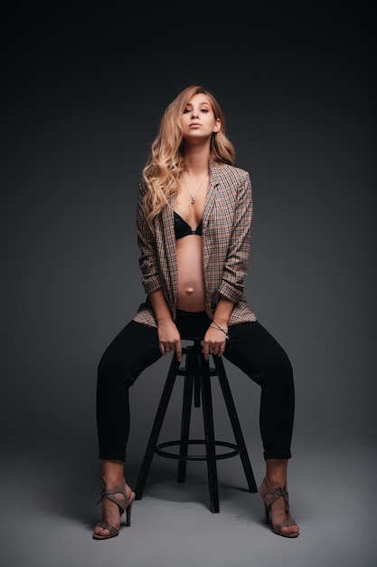 Młoda piękna kobieta w ciąży w kurtce na czarnej ścianie