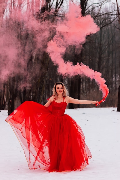 Młoda piękna kobieta w czerwonej długiej sukni na śniegu