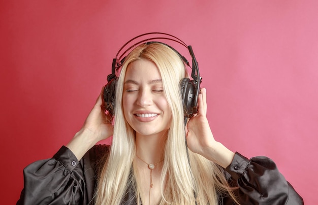 Młoda piękna kobieta w jasnym stroju ciesząca się muzyką w studio