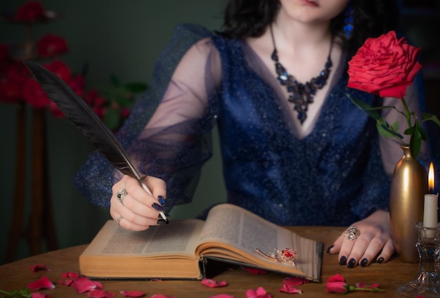 Młoda piękna kobieta w niebieskiej sukience vintage z książką na stole w ciemnym pokoju