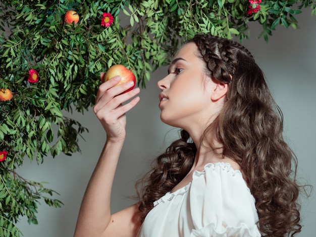 Młoda piękna kobieta w ogrodzie Eden smakuje dojrzałego owocu