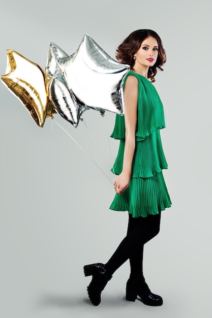 Młoda piękna kobieta w wiosennej zielonej sukience trzyma balony