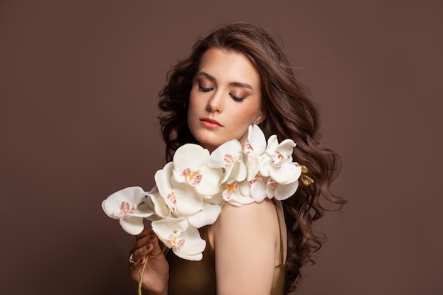 Młoda piękna kobieta z bukietem białych kwiatów profesjonalny makijaż artystyczny i doskonała kręcona fryzura