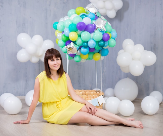 Młoda piękna kobieta z kolorowym balonem i białymi chmurami