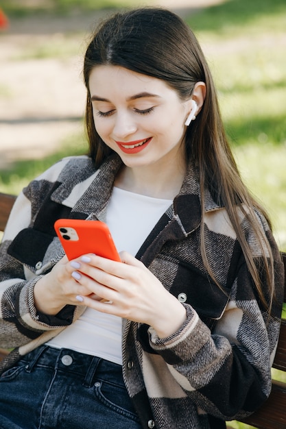 Młoda piękna kobiety pozycja na ławce używać telefon