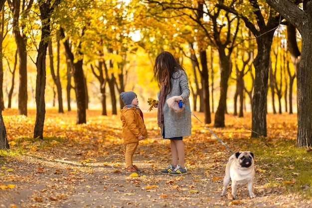 Młoda piękna mama spędza czas na spacerze z ukochanym synkiem w jesiennym parku Szczęśliwa rodzina cieszy się jesiennymi dniami