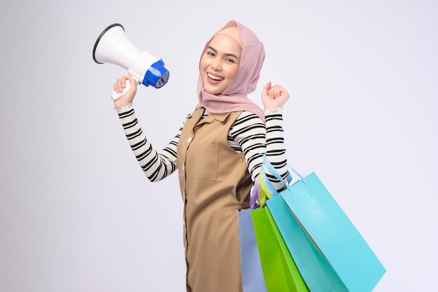 Młoda piękna muzułmanka w garniturze trzymająca kolorowe torby na zakupy na białym tle studio