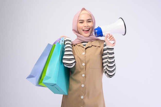 Młoda piękna muzułmanka w garniturze trzymająca kolorowe torby na zakupy na białym tle studio