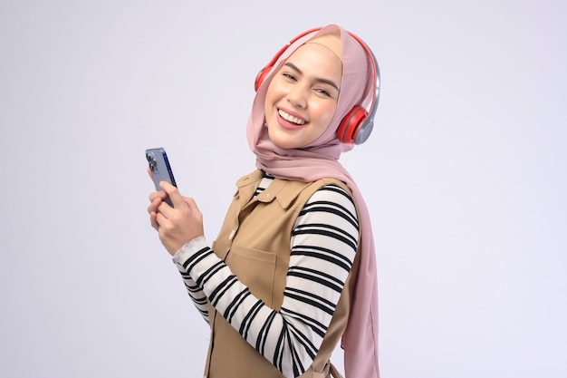 Młoda piękna muzułmańska kobieta nosząca zestaw słuchawkowy na białym tle