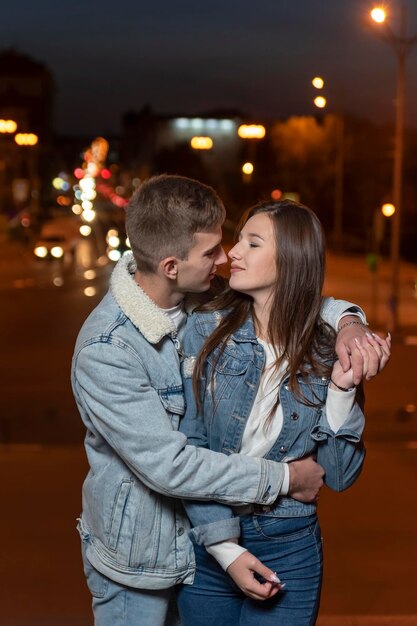 Młoda piękna para przytula się na wieczornym tle miasta Pionowa ramka