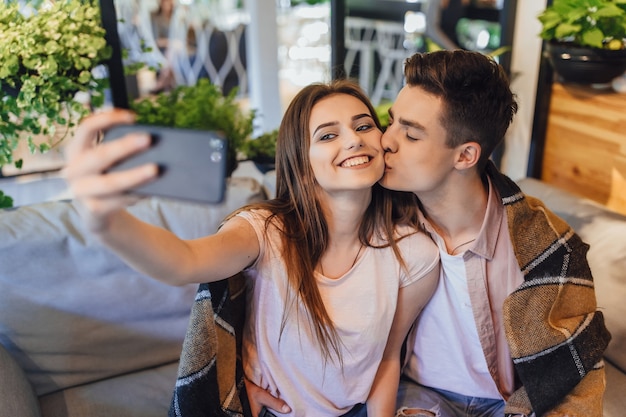 Młoda piękna para robi selfie na letnim tarasie nowoczesnej kawiarni