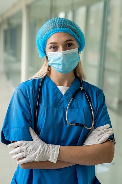 Młoda piękna pielęgniarka stojąca na korytarzu w rękawiczkach jednolitej maski. Koncepcja medycyny