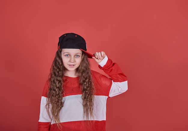 Młoda piękna śliczna dziewczyna tańczy na czerwonej ścianie, nowoczesna szczupła nastolatka w stylu hip-hop skoki