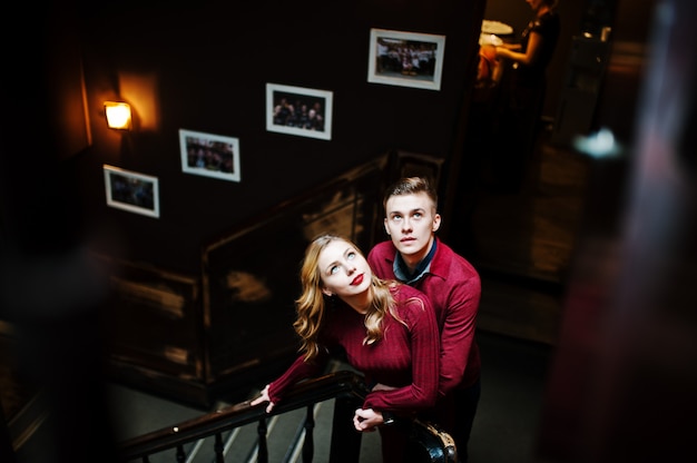 Młoda piękna stylowa para w czerwonej sukience w duże drewniane schody vintage
