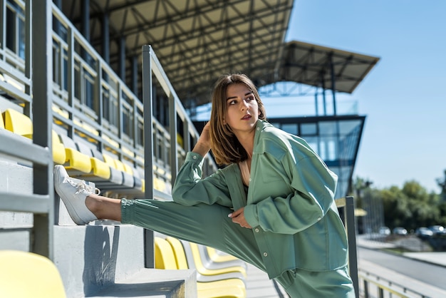 Młoda piękna szczupła kobieta w odzieży sportowej relaksuje się w pobliżu miejsc na stadionie