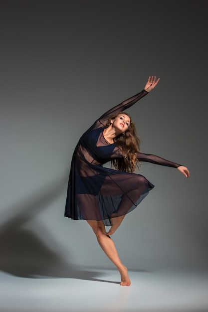 Młoda piękna tancerka w czarnej sukience pozowanie na ciemnoszarym tle studio. Nowoczesna, Współczesna, improwizacja