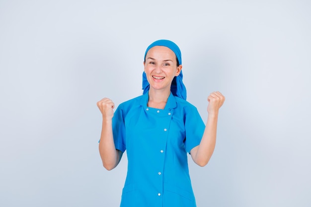 Młoda pielęgniarka czuje się szczęśliwa i podnosi pięści na białym tle